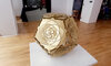 Rotated view of KAGE's Dodecahedron Platonic Solid Sculpture "The Sun" bathed in natural light, its polished brass revealing Ether's essence through sun-ray inspired patterns.