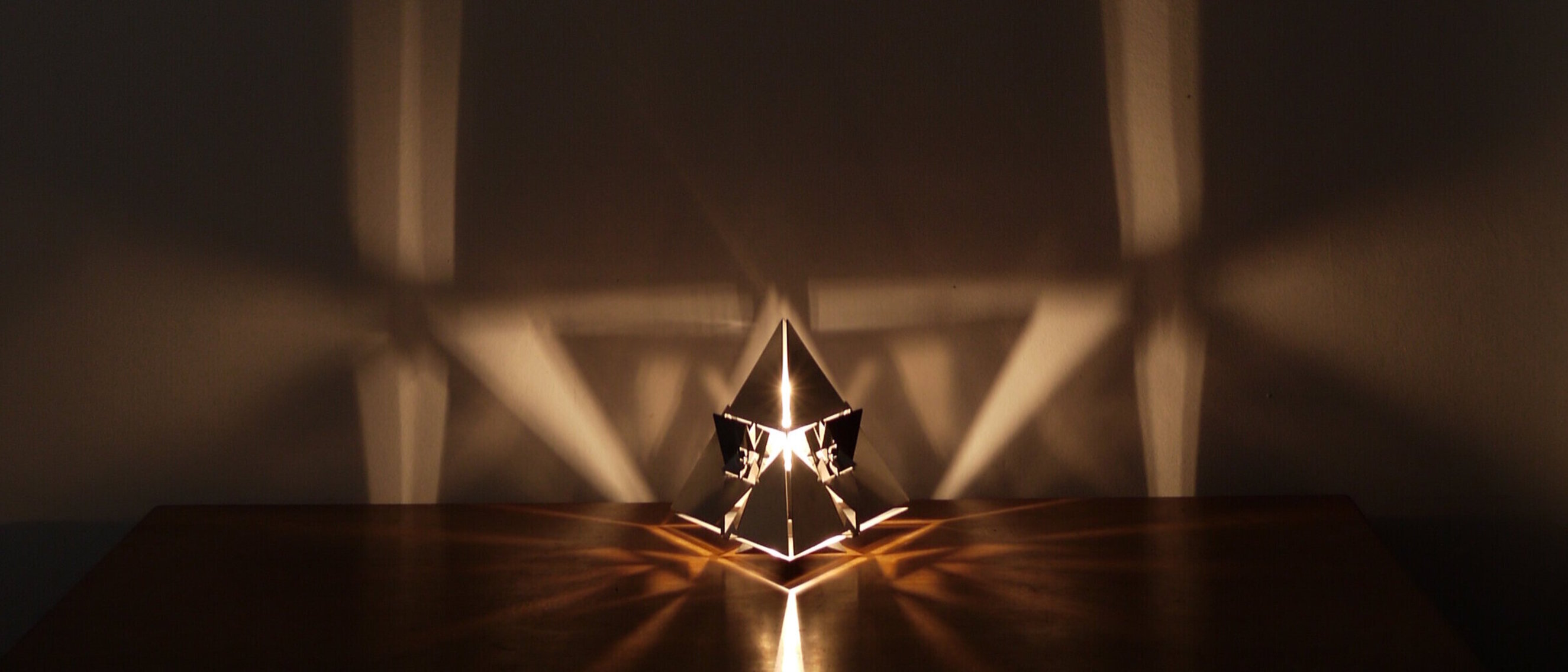 Tetraeder Platonischer Körper Lampe: Feuer
Alternative Ansicht von KAGEs Tetraeder Platonischer Körper Lampe, die den Glanz des hochglanzpolierten Edelstahls und die Fraktalmuster, die das Feuerelement repräsentieren, zeigt.